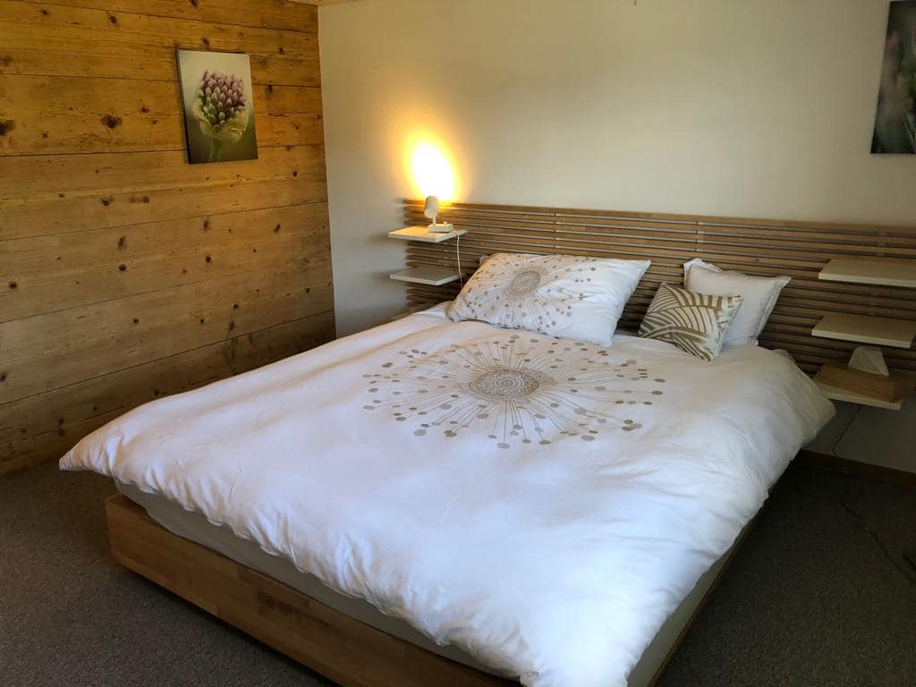 Bett mit weisser Bettwäsche und goldenem Pusteblumen Aufdruck