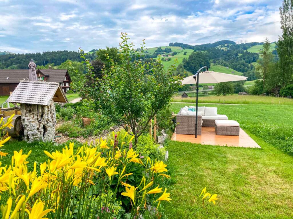 Gartenlounge mit Kissen und gelben Sommerblumen