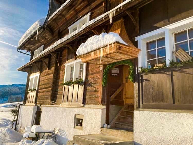Haus mit viel Schnee und Eiszapfen sowie Weihnachtsdekoration an Fenstern