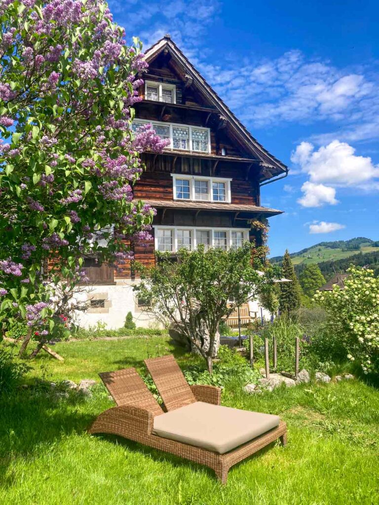 Haus und Garten mit lila Flieder und Blick auf Doppelsonnenliege