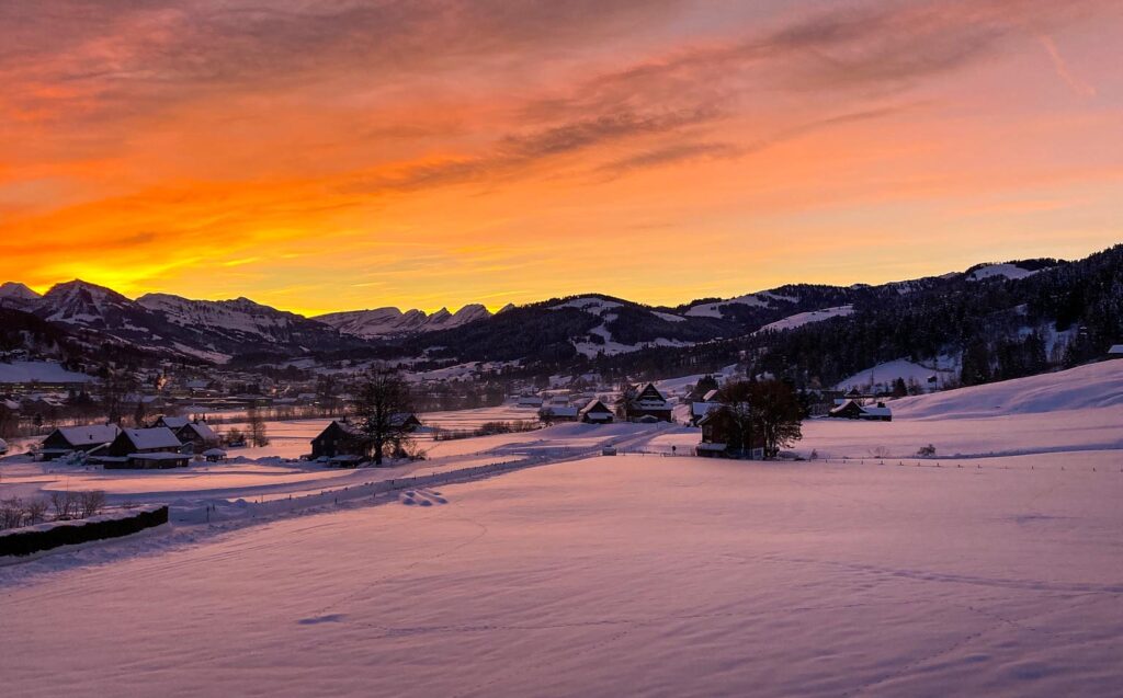 Sonnenaufgang im Winter mit rosa Wolken über Ebnat Kappel in verschneiter Märchenlandschaft